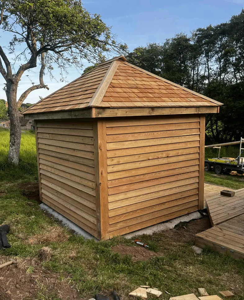 Timber-clad garden building with a shingle roof